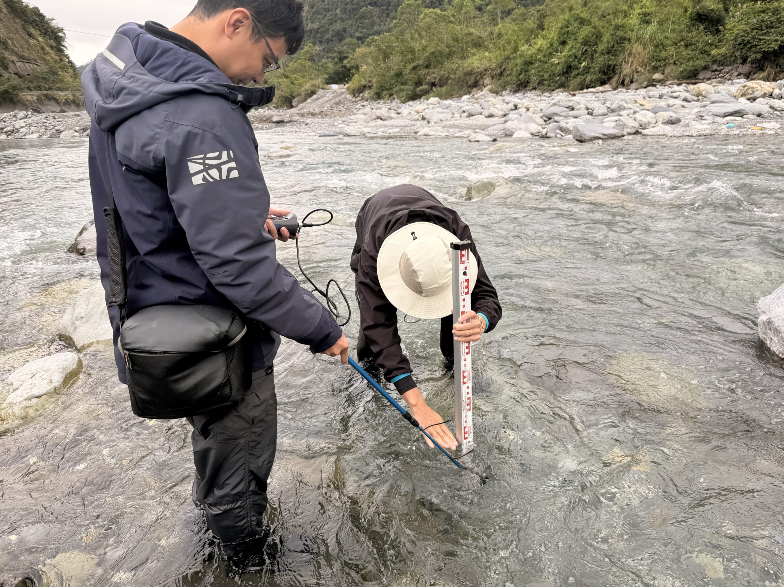 生態調查人員於河川中進行水深與流速的現地量測作業Ecological consultants measuring water depth and flow velocity in a river habitat